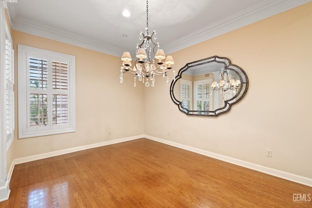 spare room with wood-type flooring, ornamental molding, and a chandelier