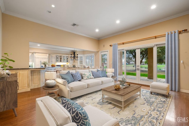 living room featuring ornamental molding, a notable chandelier, light hardwood / wood-style floors, and french doors