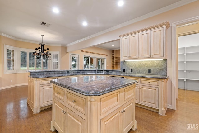 kitchen with dark stone countertops, decorative light fixtures, kitchen peninsula, and a kitchen island