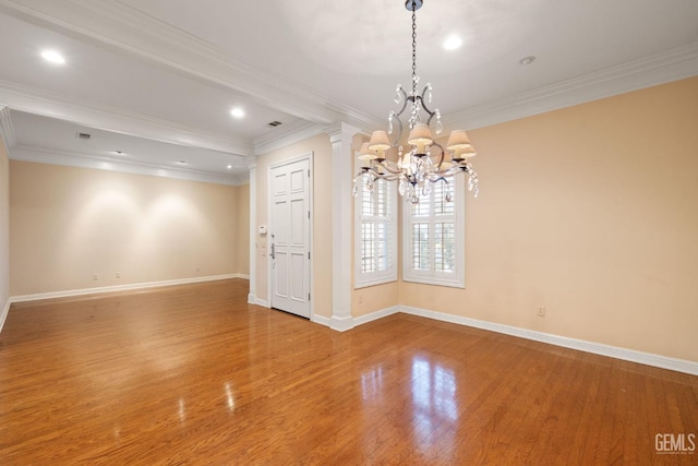 unfurnished room with an inviting chandelier, hardwood / wood-style floors, and crown molding