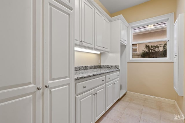 kitchen featuring white cabinetry, light tile patterned floors, and light stone counters