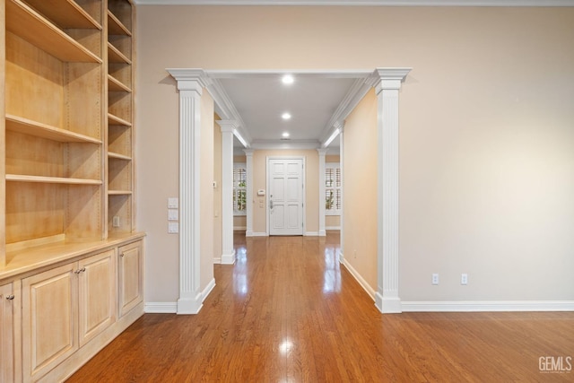 hallway featuring ornamental molding, wood-type flooring, and decorative columns