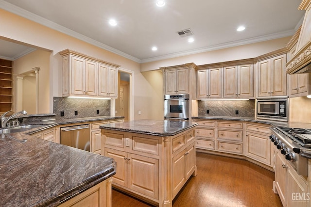 kitchen featuring light brown cabinetry, dark wood-type flooring, a center island, and appliances with stainless steel finishes