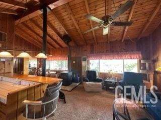 carpeted living room featuring ceiling fan, wood walls, wood ceiling, and beam ceiling