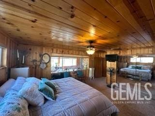 bedroom featuring carpet, wooden walls, ceiling fan, and wooden ceiling