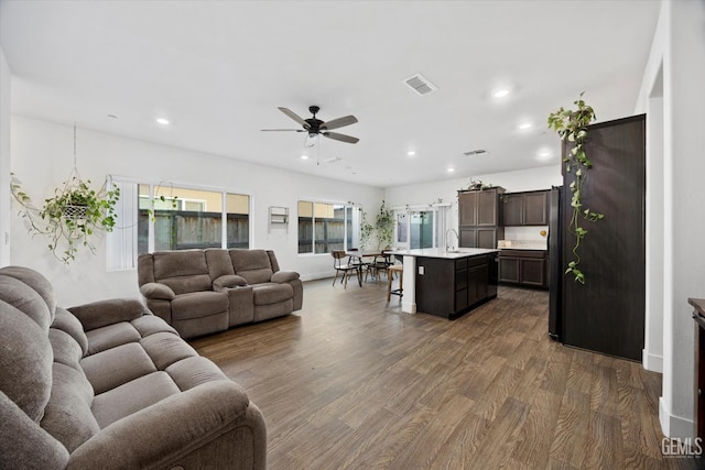 living room featuring ceiling fan, sink, and dark hardwood / wood-style flooring