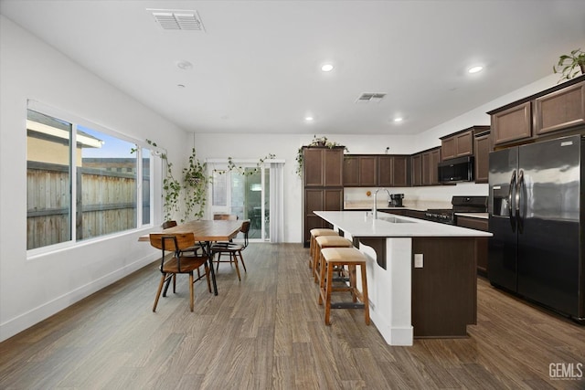 kitchen featuring dark hardwood / wood-style floors, sink, a kitchen island with sink, and black appliances