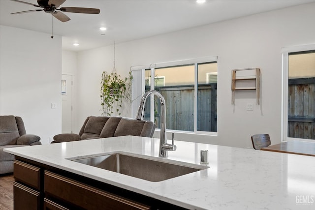 kitchen featuring hardwood / wood-style flooring, ceiling fan, light stone countertops, and sink