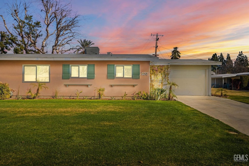 ranch-style house featuring a garage and a yard