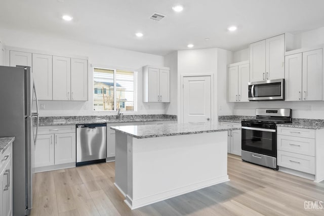 4912 Beaverhead Ave, Bakersfield, CA 93306 - kitchen featuring appliances with stainless steel finishes, a kitchen island, light wood-style floors, light stone counters, and recessed lighting