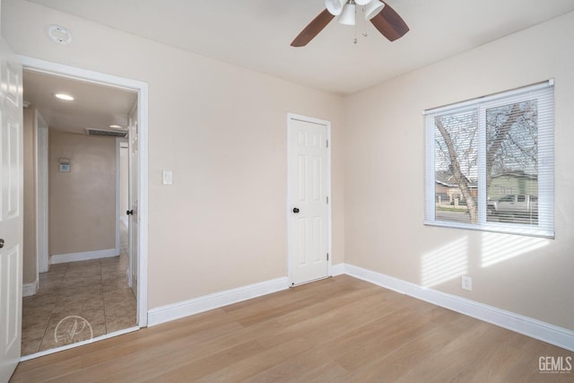 unfurnished bedroom with visible vents, light wood-style flooring, a ceiling fan, and baseboards