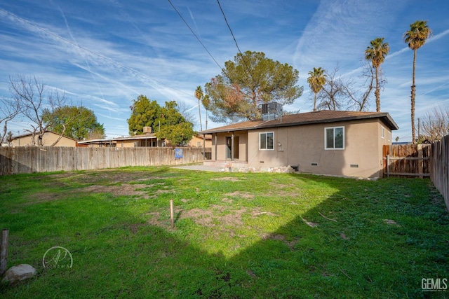 back of house with stucco siding, a lawn, a fenced backyard, crawl space, and a patio area