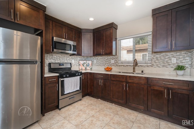 kitchen with backsplash, appliances with stainless steel finishes, light countertops, and a sink