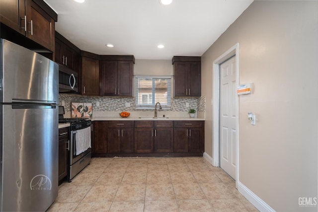 kitchen with a sink, decorative backsplash, light countertops, dark brown cabinets, and appliances with stainless steel finishes