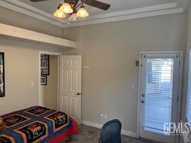 carpeted bedroom featuring a raised ceiling, a ceiling fan, and baseboards