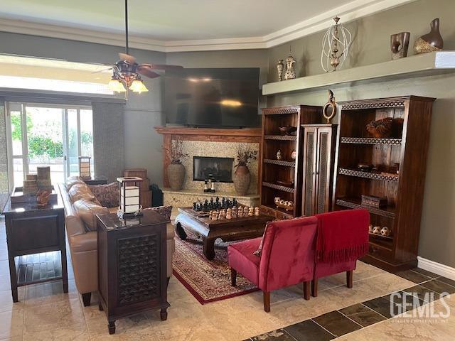 living area featuring ornamental molding, ceiling fan, and a premium fireplace
