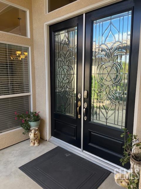 view of exterior entry with stucco siding and french doors