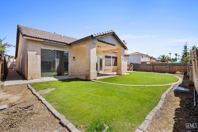 rear view of property with stucco siding, a patio area, a fenced backyard, a yard, and a tiled roof