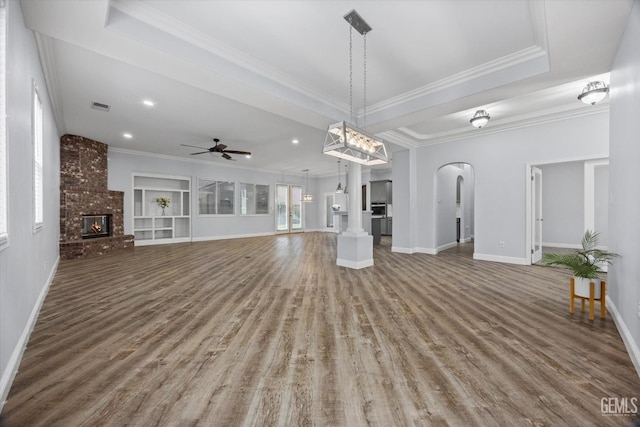 unfurnished living room with crown molding, a ceiling fan, arched walkways, and wood finished floors