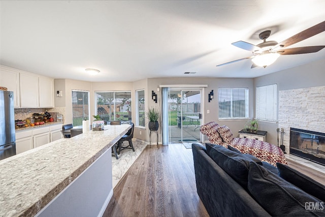 living room featuring ceiling fan, a fireplace, and light wood-type flooring