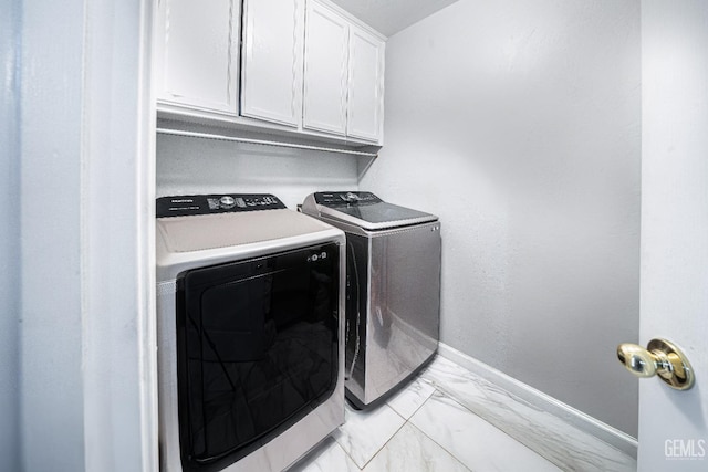 laundry room with washing machine and clothes dryer and cabinets