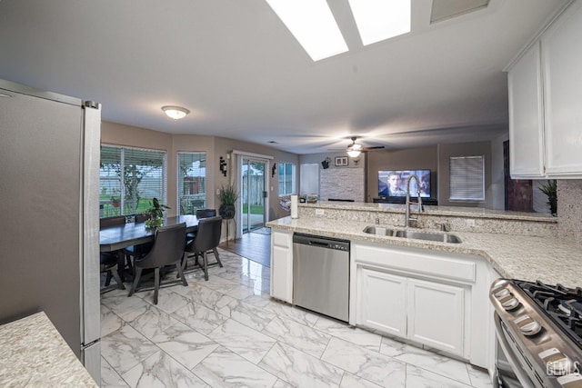 kitchen featuring decorative backsplash, appliances with stainless steel finishes, ceiling fan, sink, and white cabinets