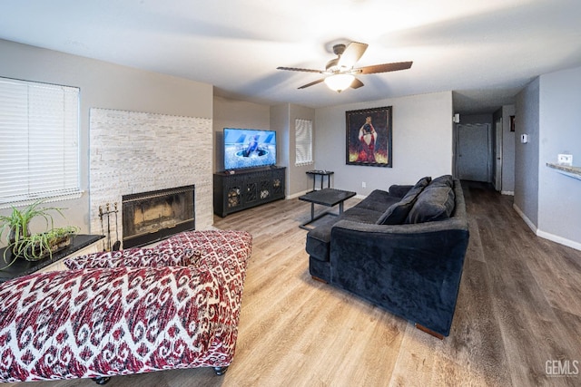 living room with hardwood / wood-style floors, a stone fireplace, and ceiling fan