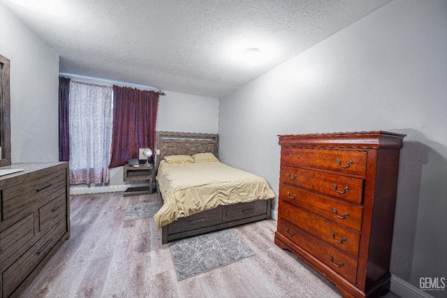 bedroom with light wood-type flooring and a textured ceiling