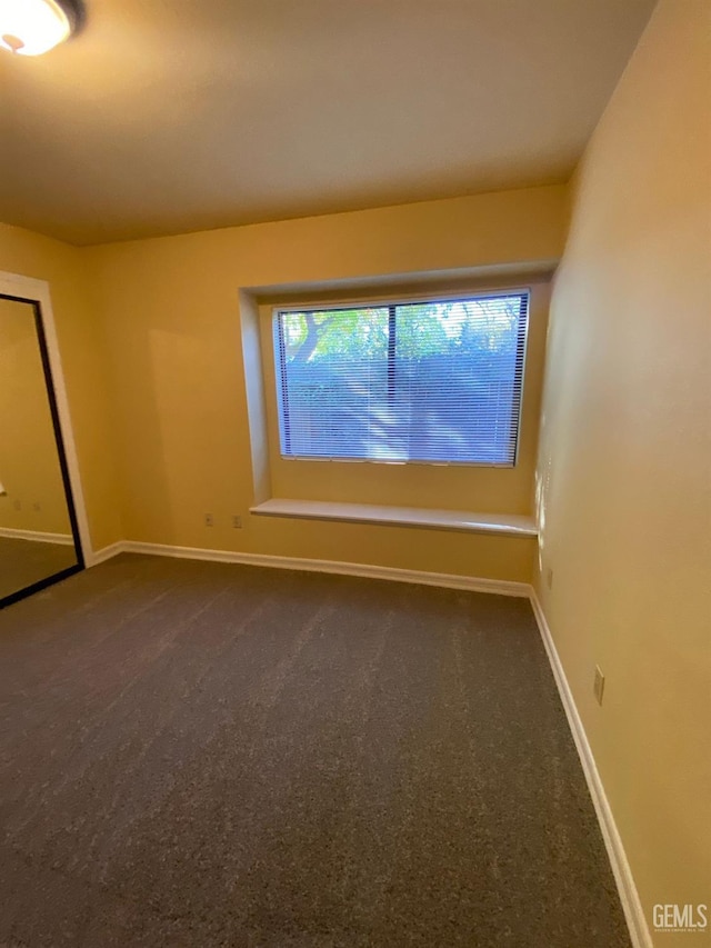 empty room featuring dark carpet and baseboards