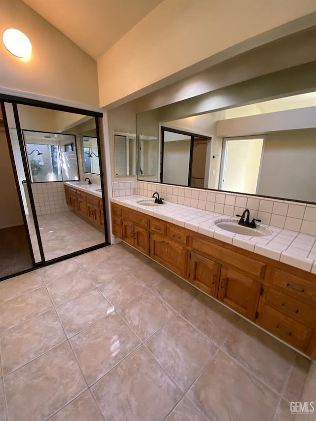 full bathroom featuring lofted ceiling, tile patterned flooring, a sink, decorative backsplash, and double vanity