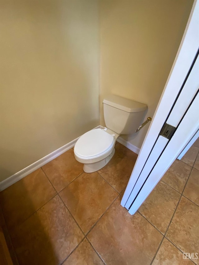 bathroom with baseboards, toilet, and tile patterned floors