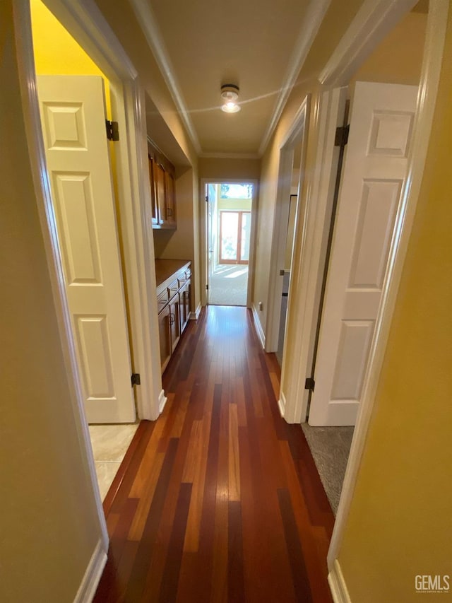 corridor with dark wood-style floors, baseboards, and crown molding