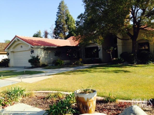 view of front of house featuring a garage, a tile roof, driveway, stucco siding, and a front yard