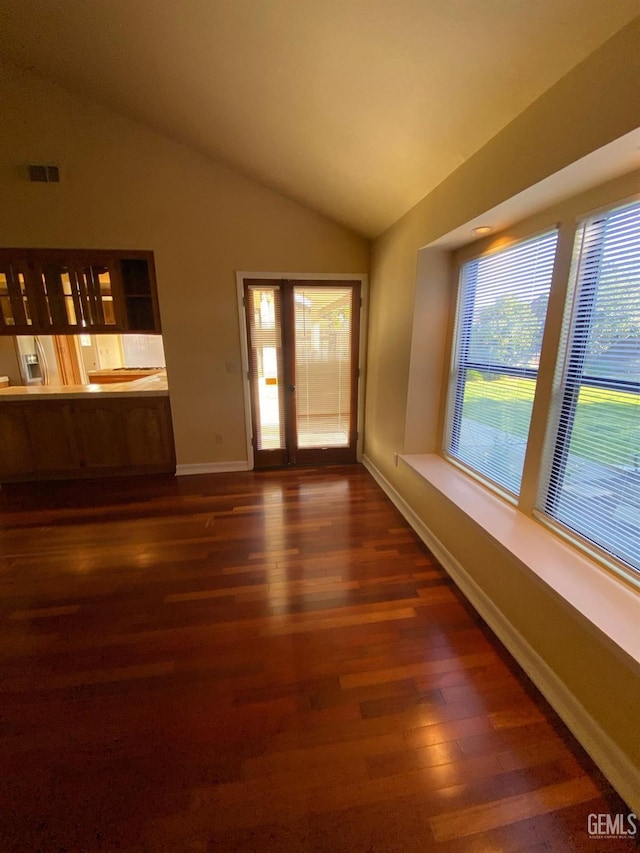 spare room featuring vaulted ceiling, dark wood-type flooring, visible vents, and baseboards