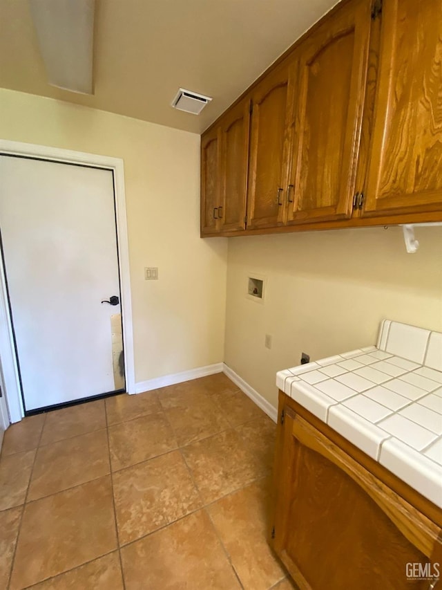 washroom featuring light tile patterned floors, washer hookup, visible vents, baseboards, and cabinet space