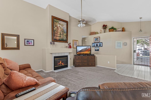 carpeted living room with a tile fireplace, ceiling fan, and vaulted ceiling