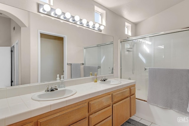 bathroom featuring shower / bath combination with glass door, vanity, tile patterned floors, and lofted ceiling