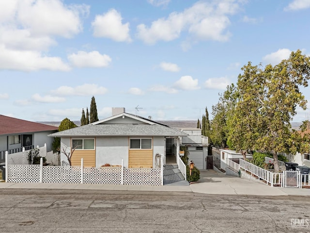 726 D St, Taft, CA 93268 - view of front facade with roof mounted solar panels, fence, a shingled roof, stucco siding, and concrete driveway