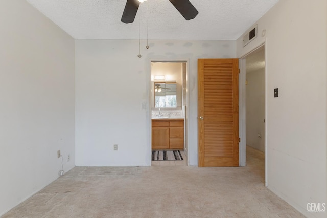 726 D St, Taft, CA 93268 - unfurnished bedroom featuring visible vents, connected bathroom, a sink, a textured ceiling, and light colored carpet