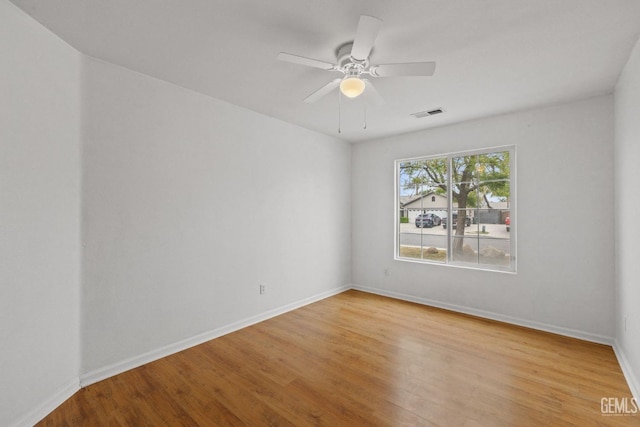 empty room featuring baseboards, a ceiling fan, visible vents, and light wood-type flooring