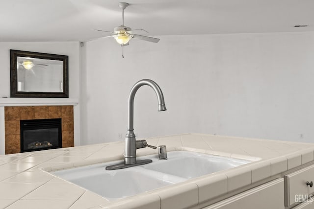 interior details with a ceiling fan, a sink, and a fireplace