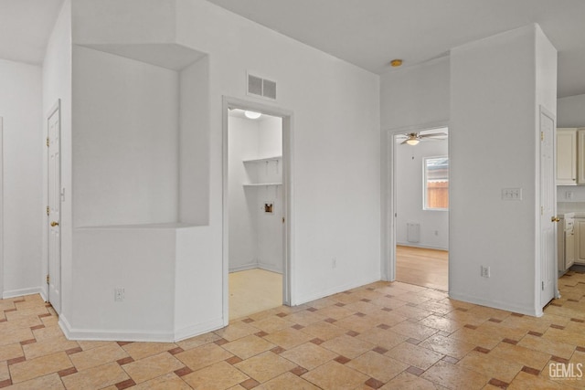 interior space featuring baseboards, visible vents, stone finish floor, and ceiling fan