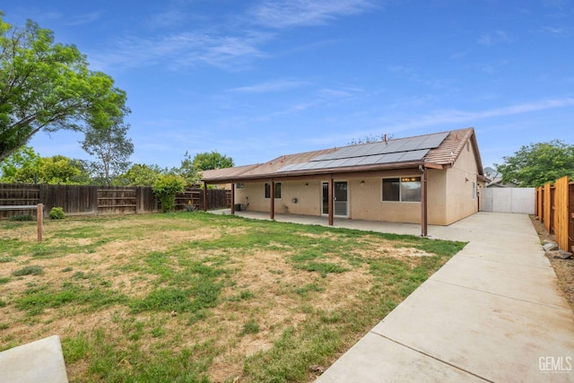 back of property featuring a fenced backyard, solar panels, a patio area, a yard, and stucco siding