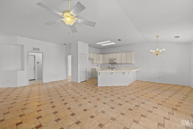kitchen with a peninsula, open floor plan, visible vents, and white microwave