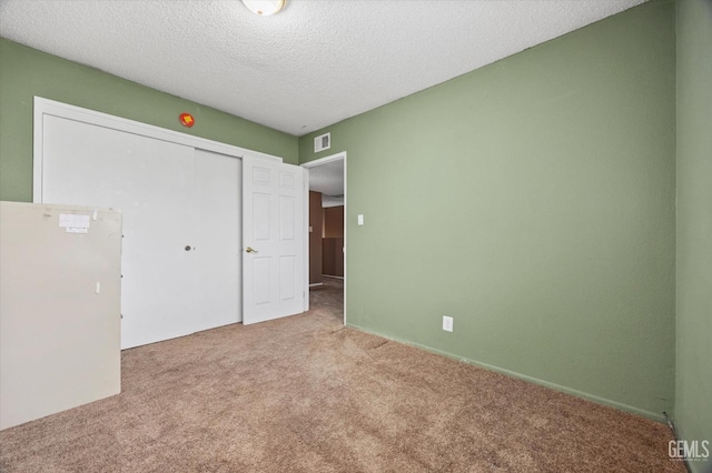 unfurnished bedroom with carpet floors, a closet, and a textured ceiling