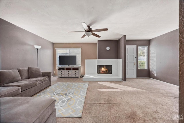 living room with ceiling fan, a multi sided fireplace, carpet, and a textured ceiling