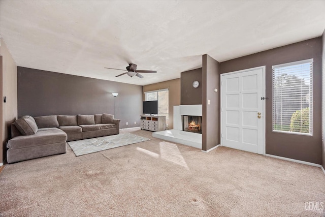 unfurnished living room with ceiling fan, a multi sided fireplace, and light colored carpet