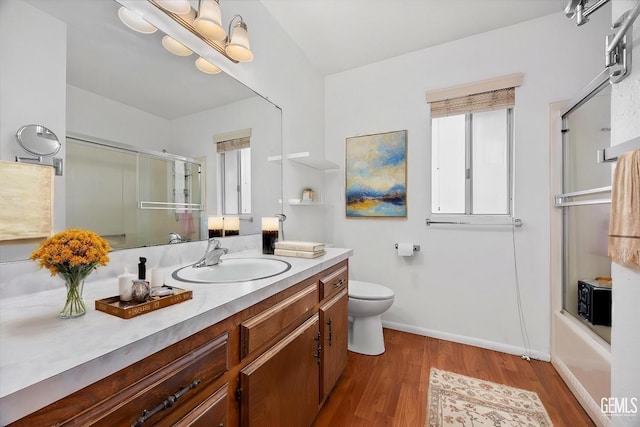 full bathroom with enclosed tub / shower combo, wood-type flooring, vanity, and toilet