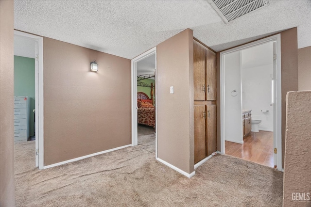 corridor featuring light colored carpet and a textured ceiling