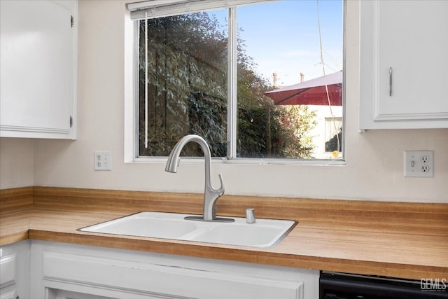 interior details with dishwasher, white cabinetry, and sink